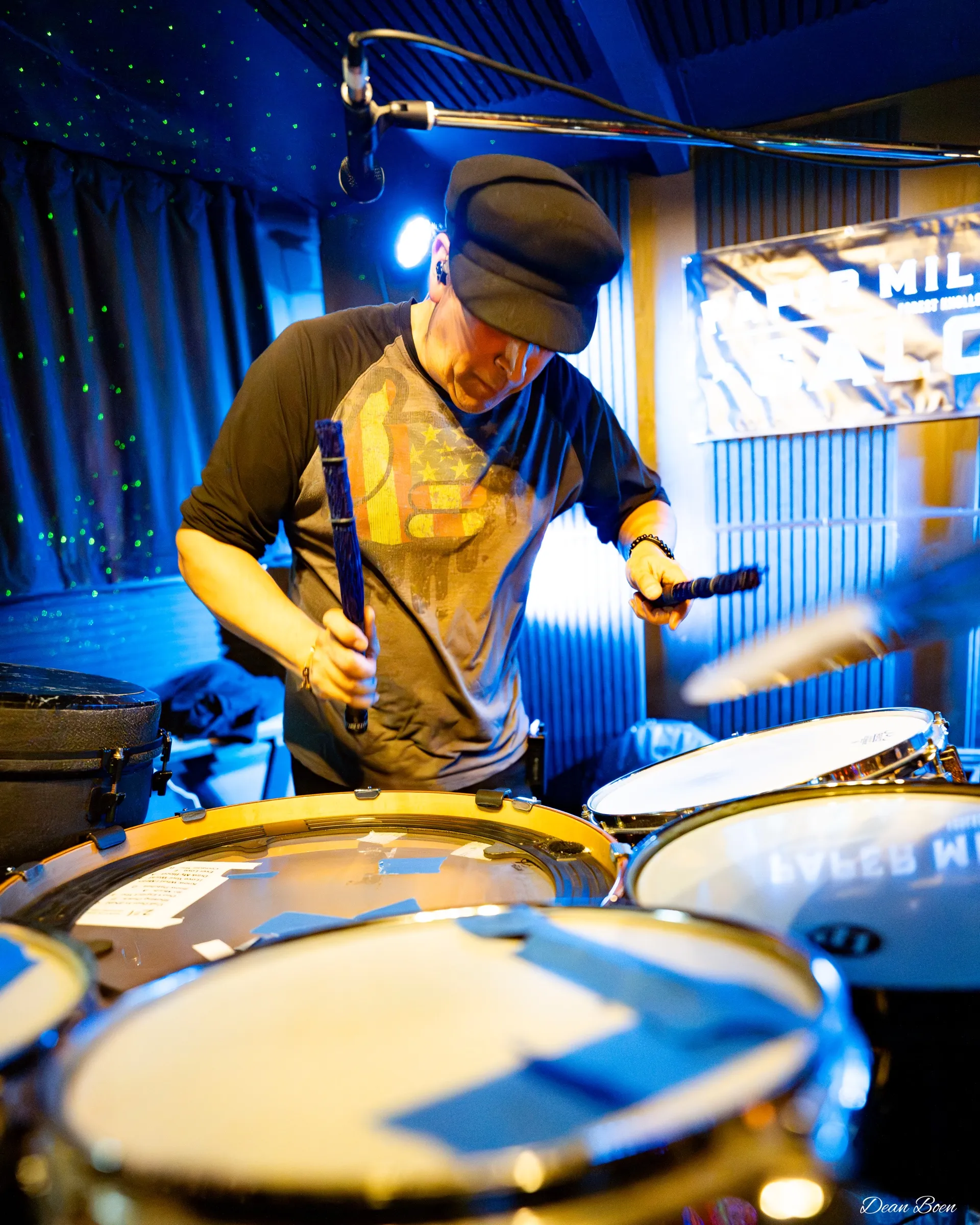 Drummer playing with mallets, seen from just behind the kit