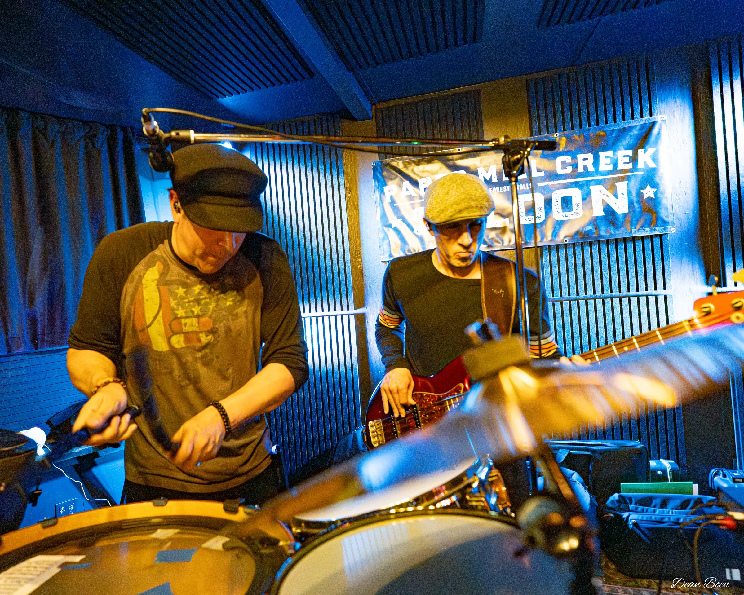 Drummer and bassist on stage in front of the Paper Mill Creek Saloon banner